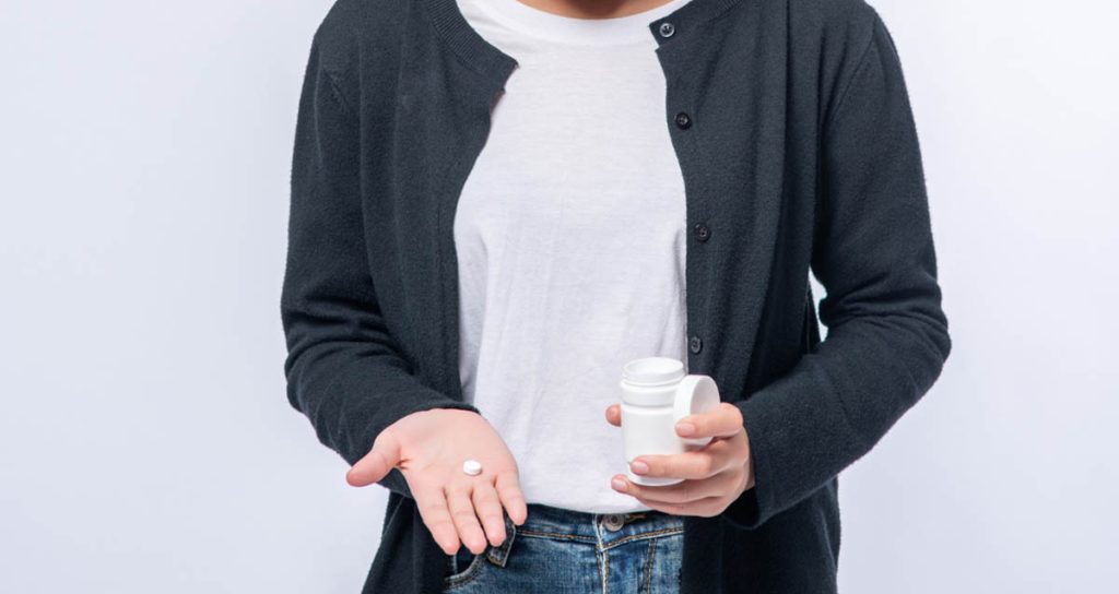 Woman with a health supplement and medications for her gut